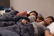 Elternpaar liegt mit Kind in der Mitte im Doppelbett elternbett